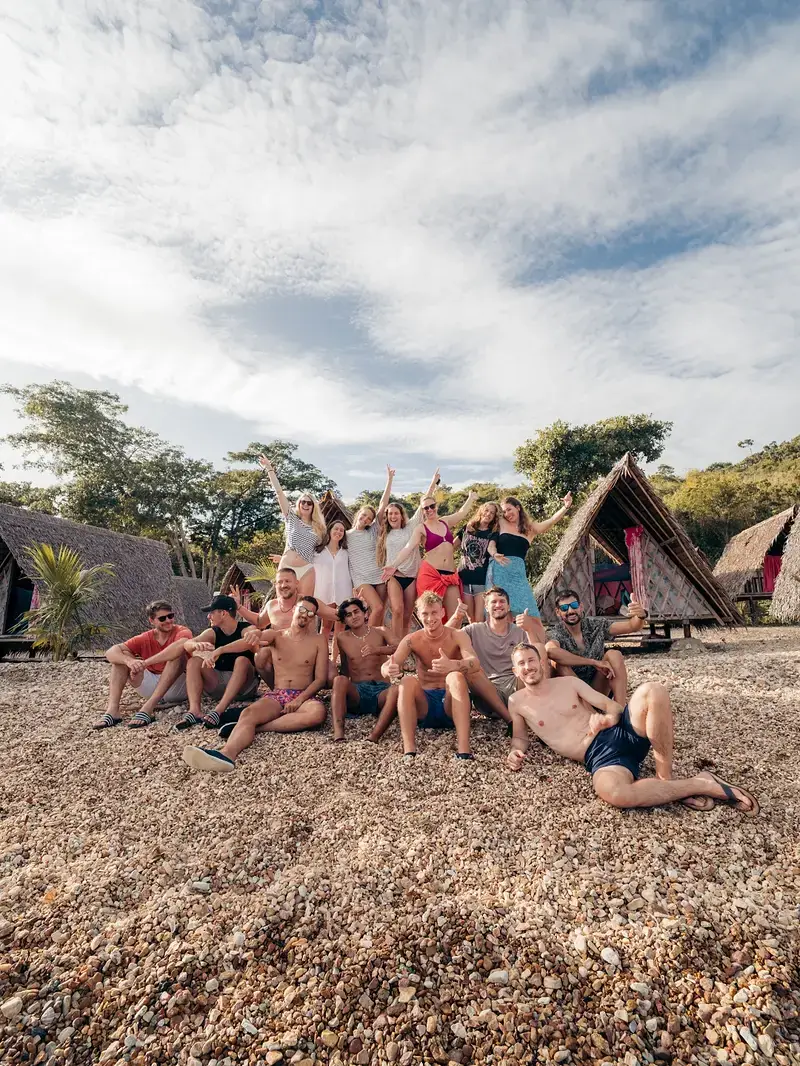 Small expedition group around a Linapacan beach campsite at sunset